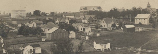 Old photo of a wide-view shot of a hillside with simple houses and buildings