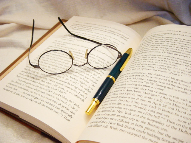 glasses and a pen on an open book