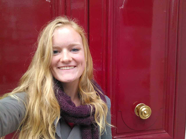 Blonde student posing in front of a red-painted door