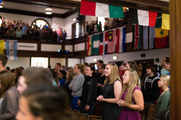 Students in chapel with flags of countries hanging above