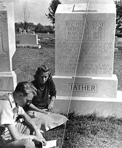 Students sitting by a large gravestone