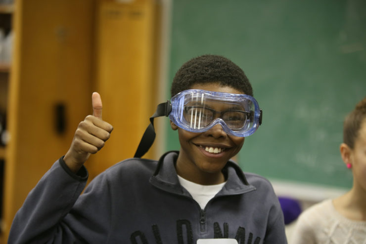 child wearing safety goggles and giving a thumbs-up