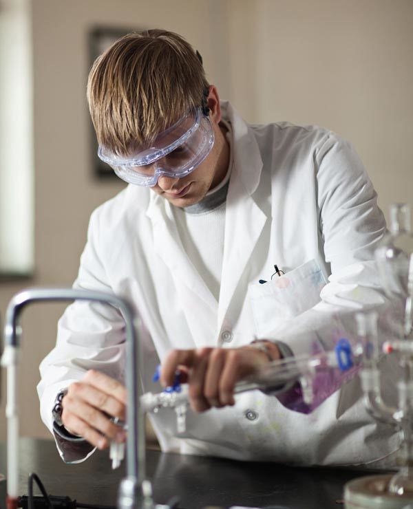 chemistry student pouring a solution into a beaker