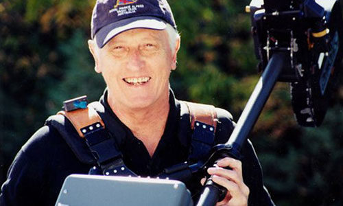 Garret Brown smiling and holding a steadicam