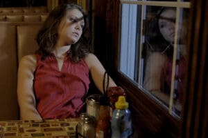 Student actress sitting in a restaurant booth, looking outside