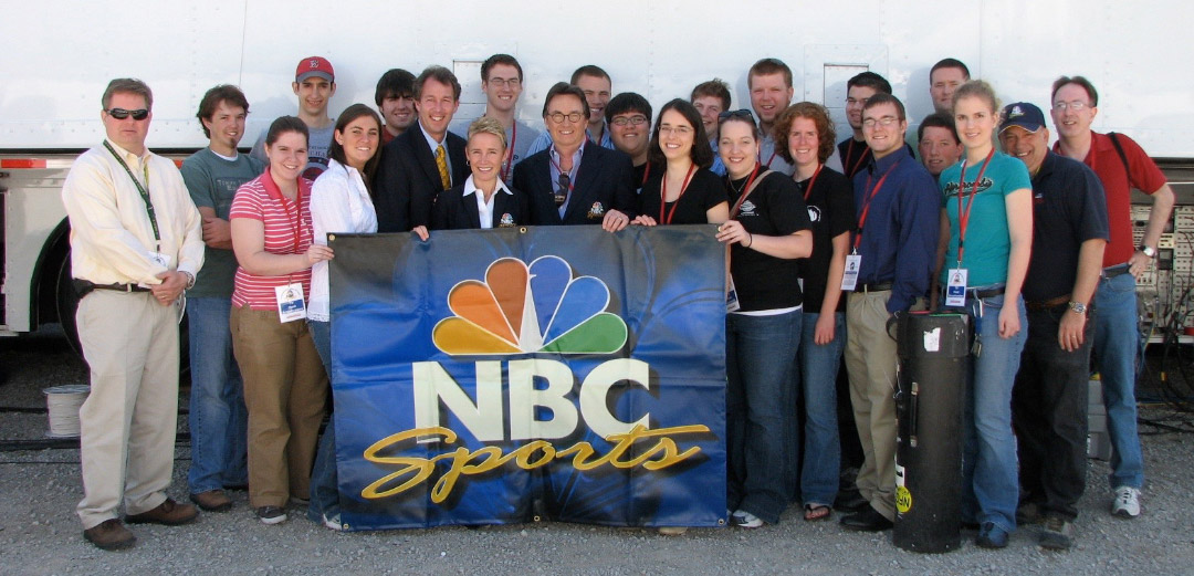 Student interns posing with an NBC Sports banner