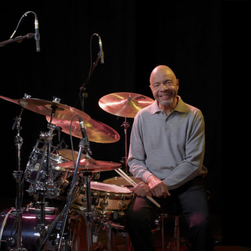 person sitting at a drum set and smiling
