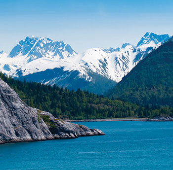 Ocean, forest and snowcapped mountains