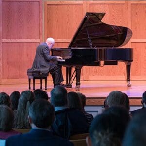 Professor playing the piano on stage