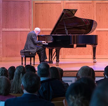 Professor playing the piano on stage