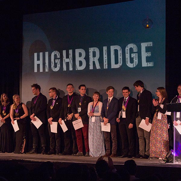 Students standing on stage holding awards