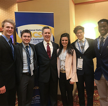 Students in business suits posing for a photo at a conference