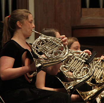 Students playing brass instruments in orchestra