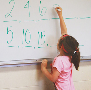 A child writing numbers on a whiteboard