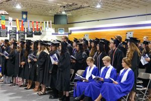 student graduates standing at commencement