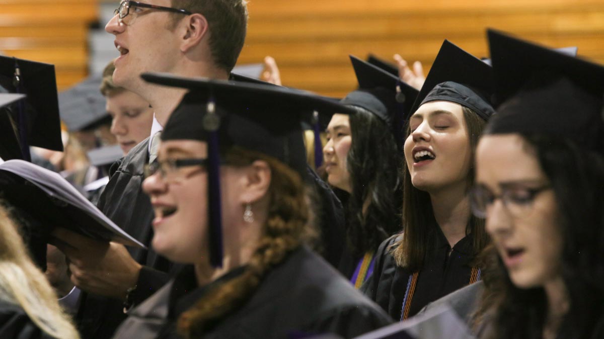 student graduates singing at commencement