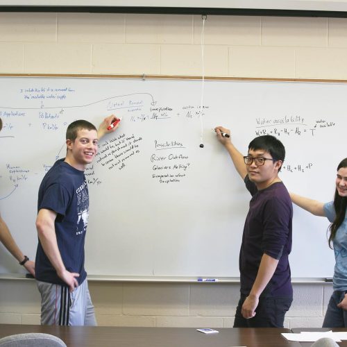 math students writing on a whiteboard