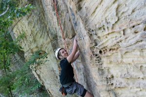 student climbing a cliff face