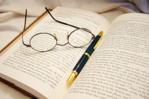 a pair of glasses and a pen on an open book