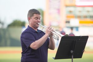 person playing trumpet at a baseball field