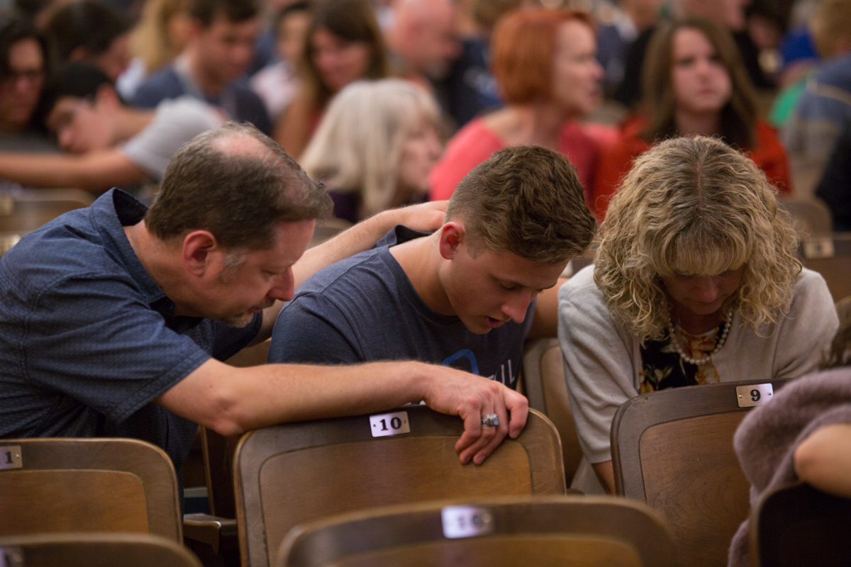 student and parents praying in Hughes Auditorium