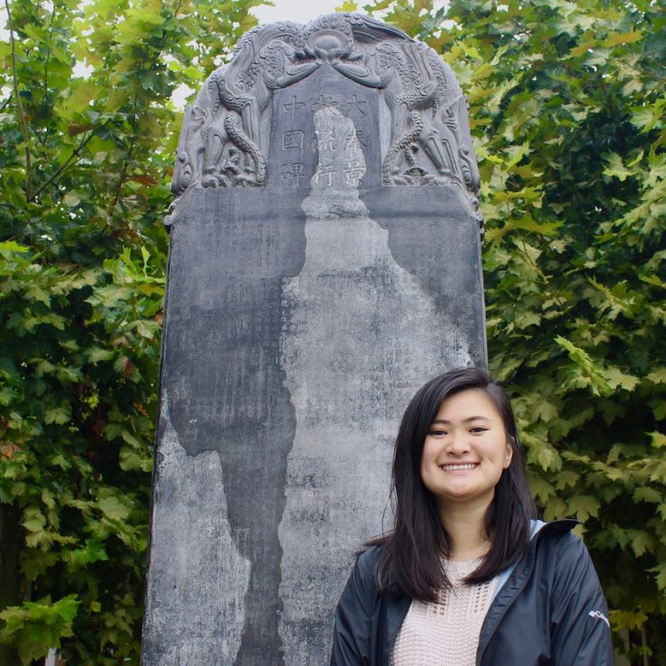 student standing in front of a large sculpture in China