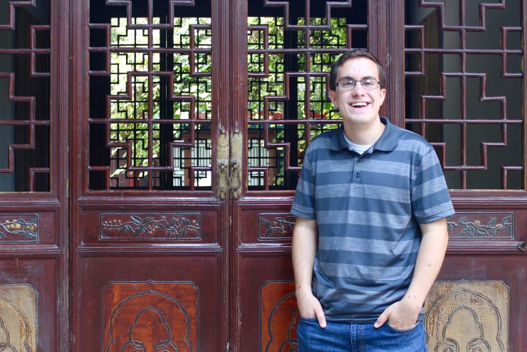 student in front of wooden doors in China