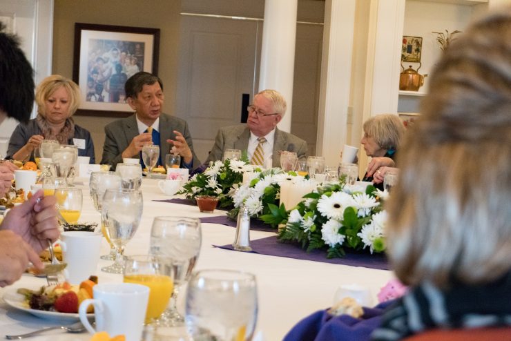 students, faculty, staff, and ambassadors at a long banquet table