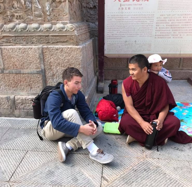 student conversing with a monk on a street in China