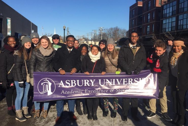 students from all races holding a banner and marching on Martin Luther King, Jr. Day