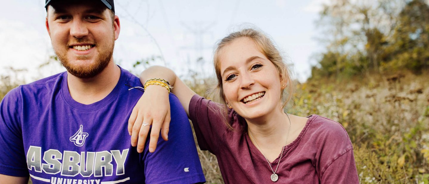 Two Asbury Students sitting in a field smiling for a photo