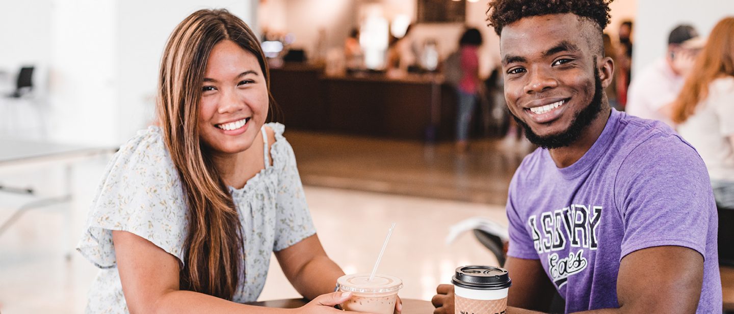 Two Asbury University students at a coffee shop on campus and smile for a photo