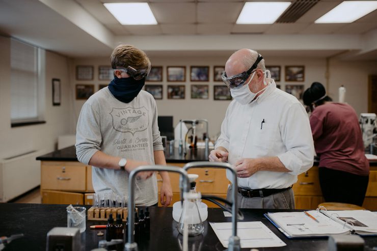 A professor and an Asbury student both in face masks work on a science experiment in a classroom laboratory