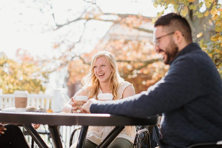 Three Asbury University students, two visible, sit around a table outdoors drinking coffee