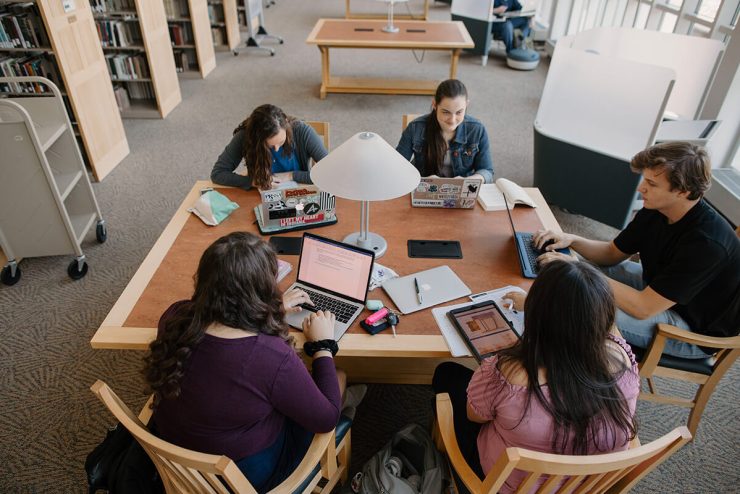 Five Asbury University students sit around a library table with their laptops out