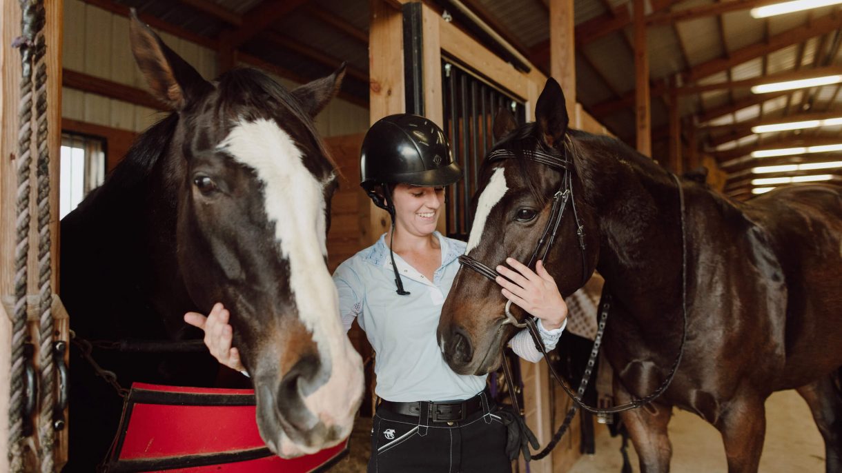 Asbury University Undergraduate Student smiles and works with horses in a stable