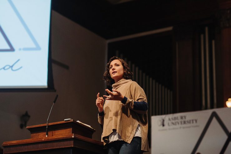 A woman confidently speaks onstage at Asbury University