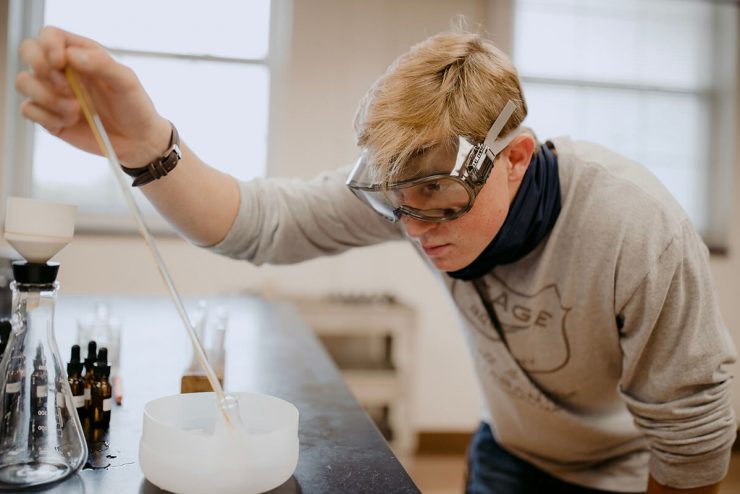 An Asbury University student works in a science lab with safety goggles on